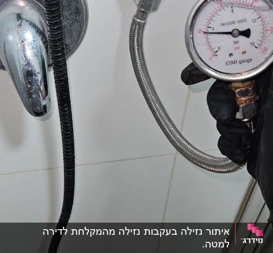 מד לחץ מחובר לצינור מתכת ליד ברז במקלחת